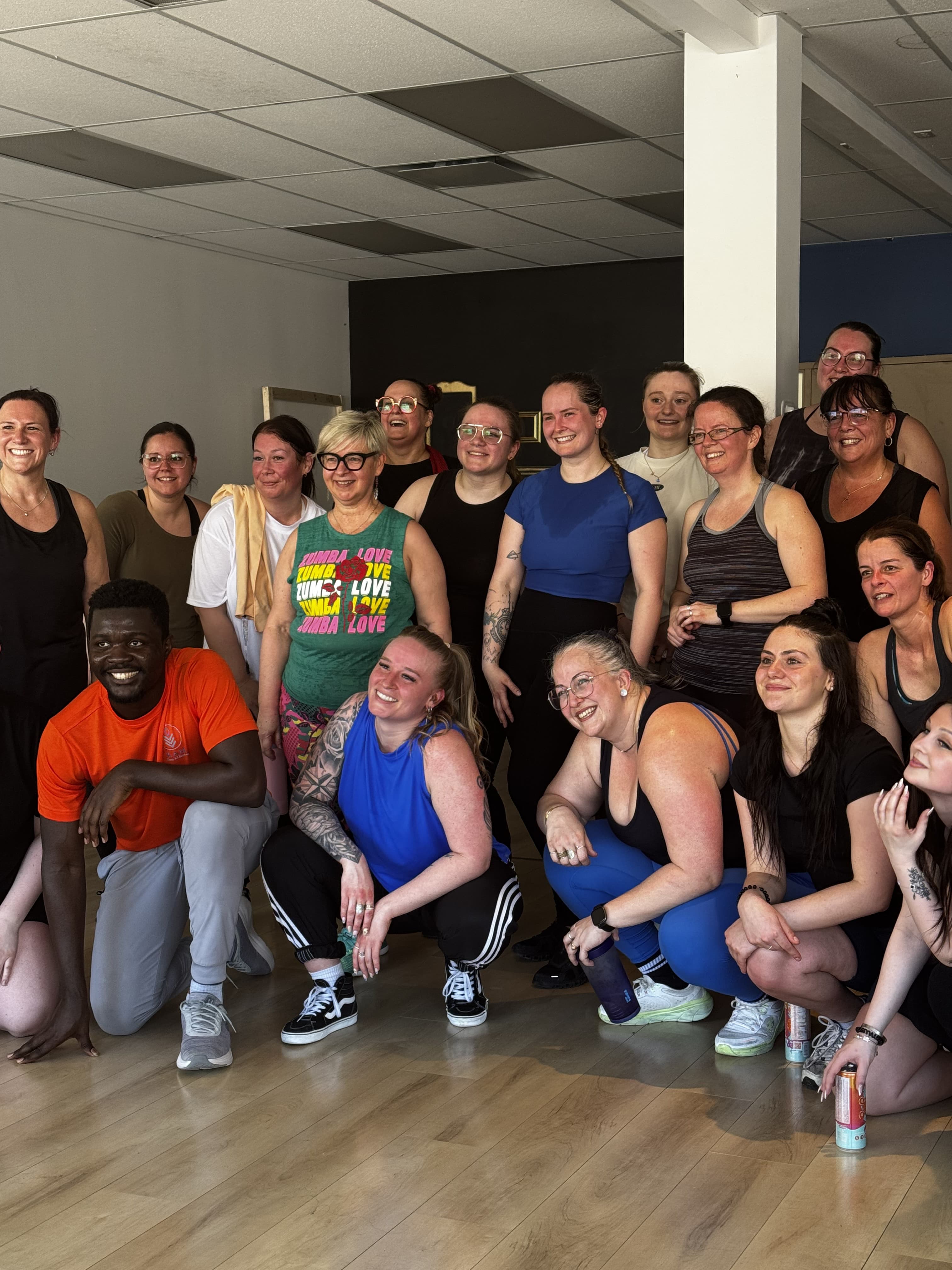 Une vingtaine de membres de la KAM-munauté sourient ensemble au studio après une soirée